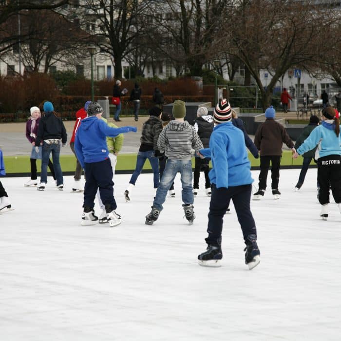 Evening skating on a well-lit synthetic ice rink in a town square