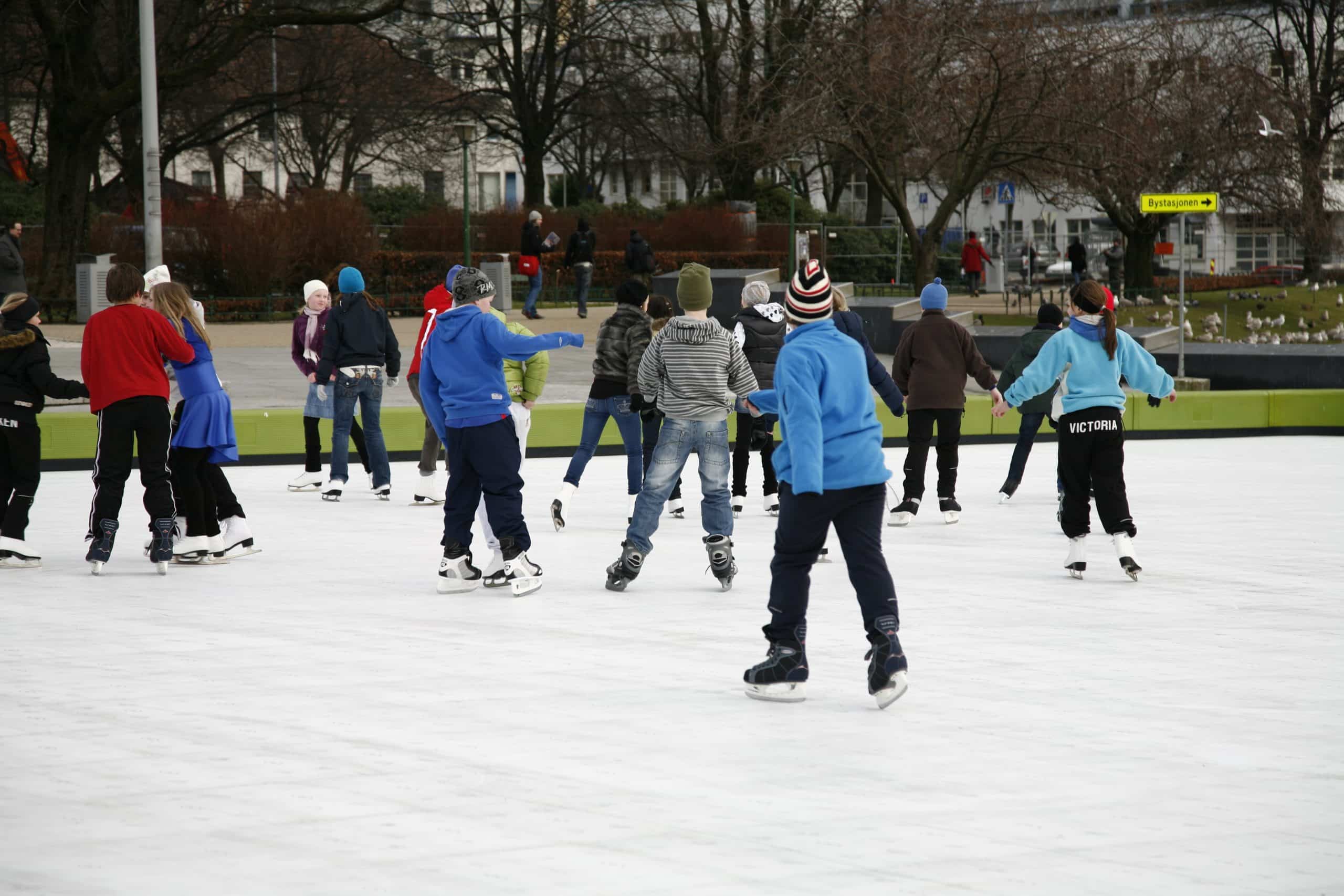 Evening skating on a well-lit synthetic ice rink in a town square