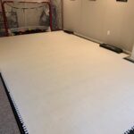 Indoor / outdoor synthetic ice hockey training area inside a home using Skate Anytime panels.